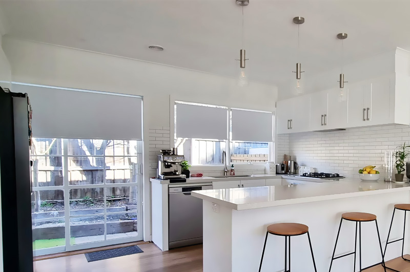 After: white kitchen with subway tiles, an island bench, pendant lights and stools