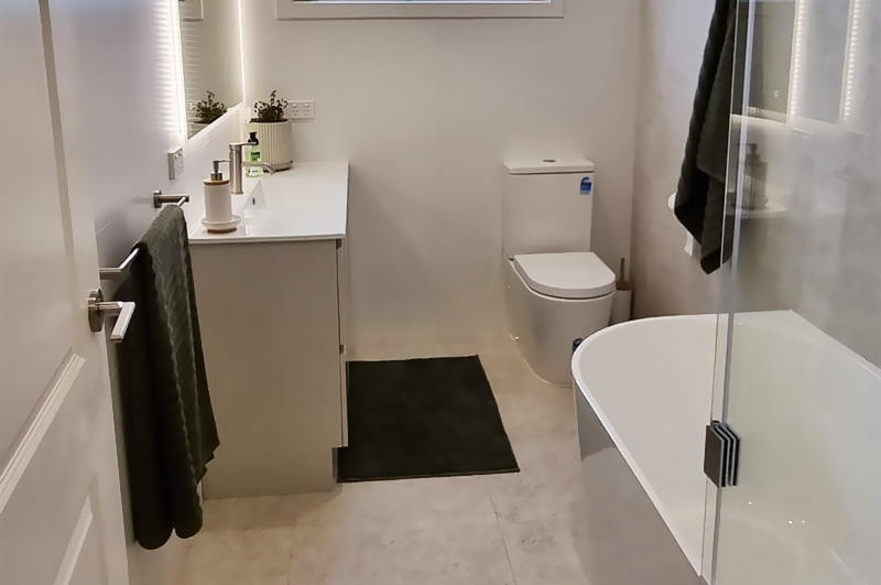 After: renovated bathroom with a freestanding bath, white vanity and toilet