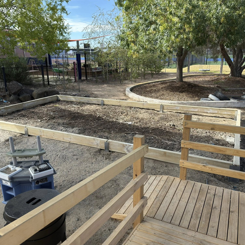 Timber ramp with handrails beside new timber garden bed edging in a play yard