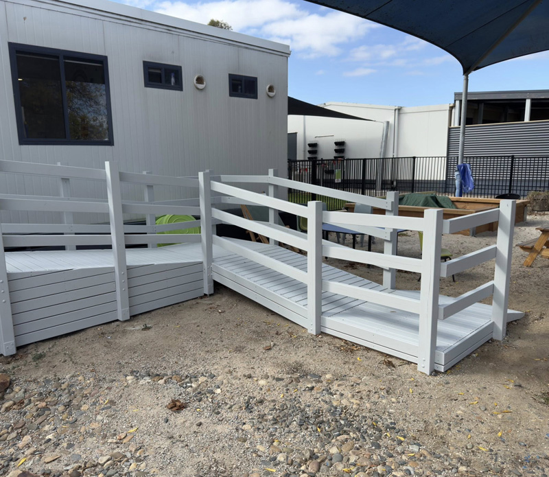 Grey painted timber ramp with railings leading to a portable building