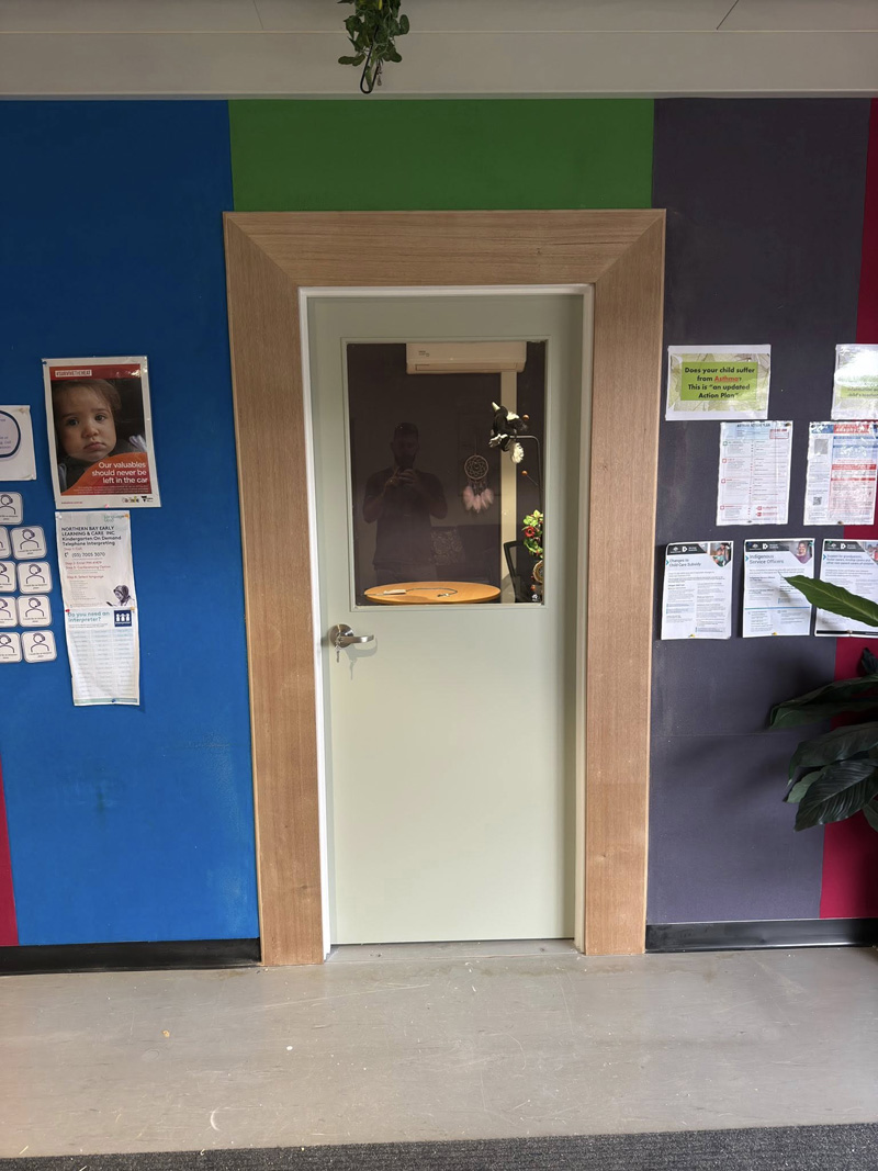 Timber door frame around a doorway in a room with colourful painted walls