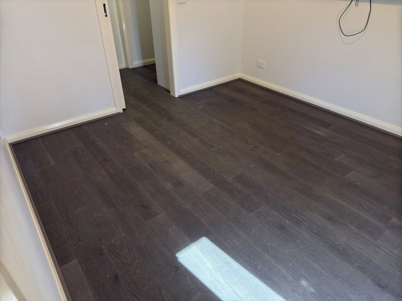 Dark timber-look flooring in a bedroom with sunlight on the floor