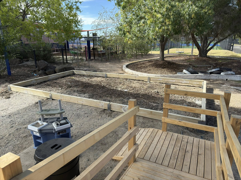 Timber ramp with handrails beside new timber garden bed edging in a play yard