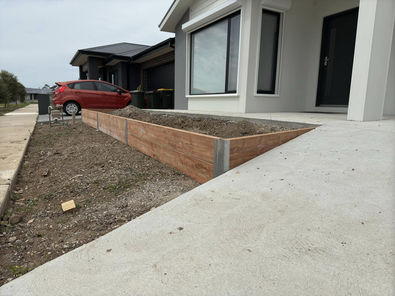 Timber sleeper garden bed along a new concrete driveway at a new home