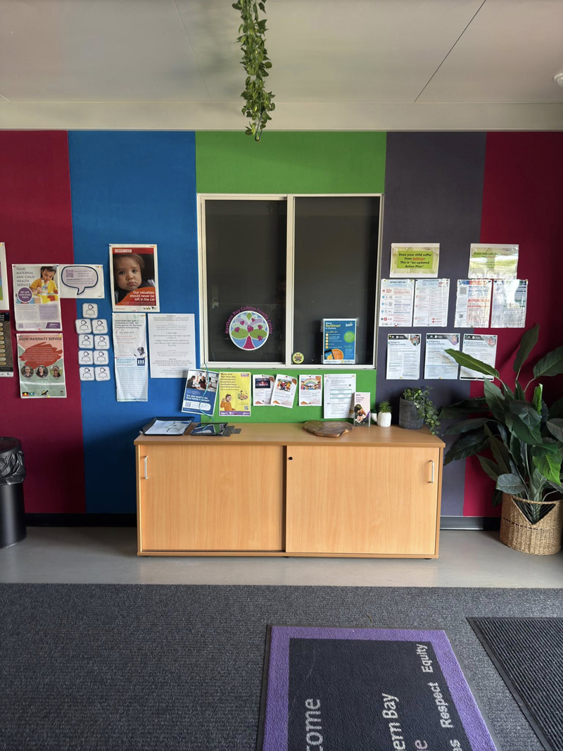 Room with red, blue, green and purple painted feature walls and a timber cabinet