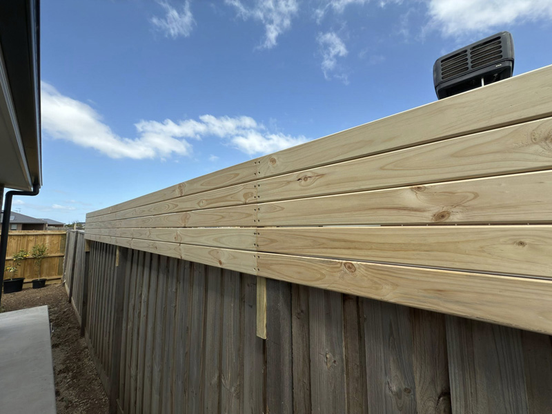 New pine boards added along the top of a timber paling fence