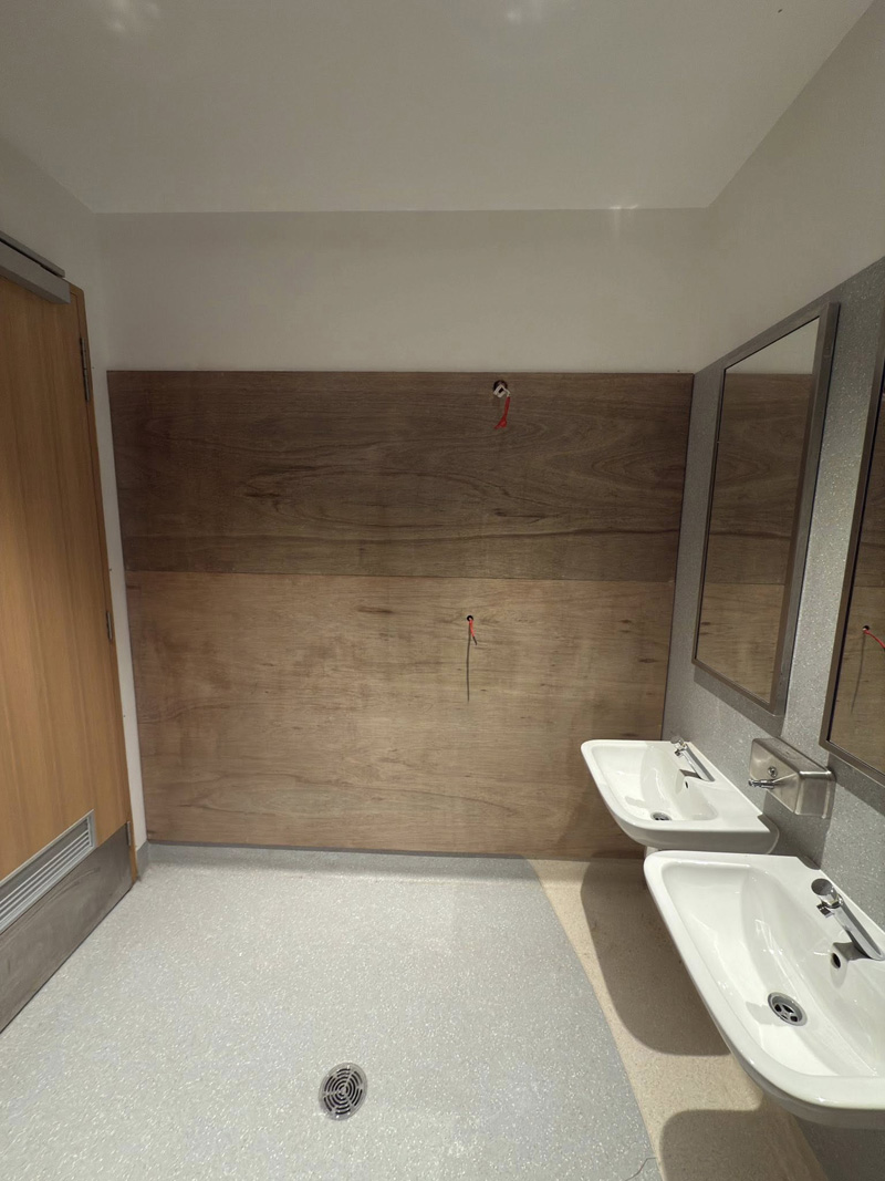 Washroom with timber-look wall panels and two small hand basins