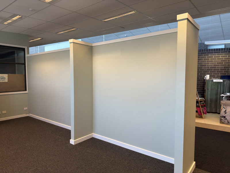 Painted partition walls with a capped pier in an open carpeted room